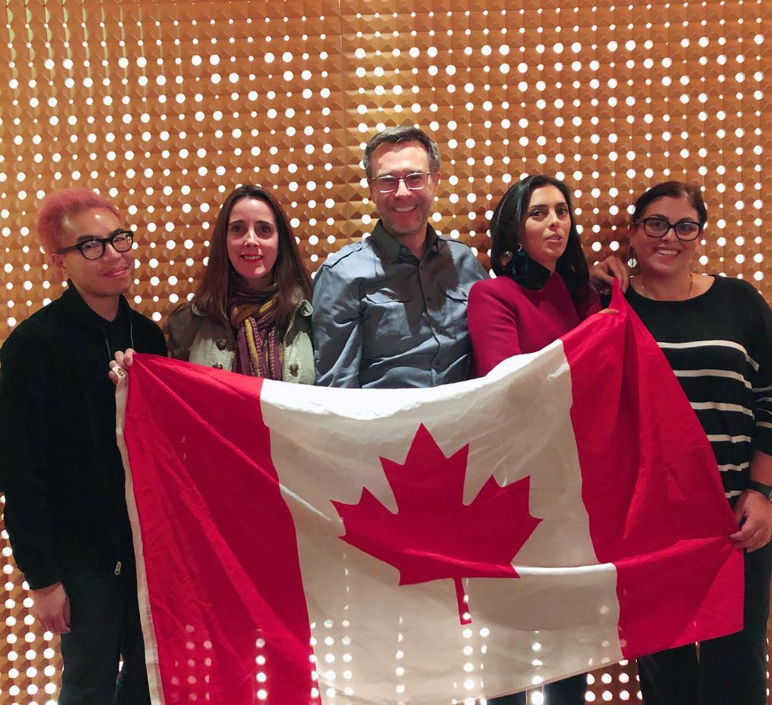 Five people holding up a Canadian flag.