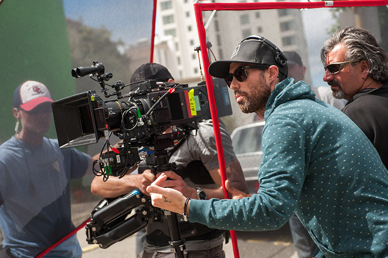 A film director standing beside a camera giving direction on set