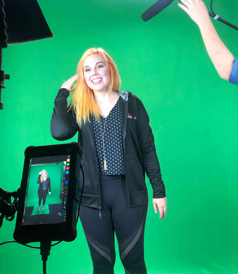 A woman being interviewed in front of a green screen.