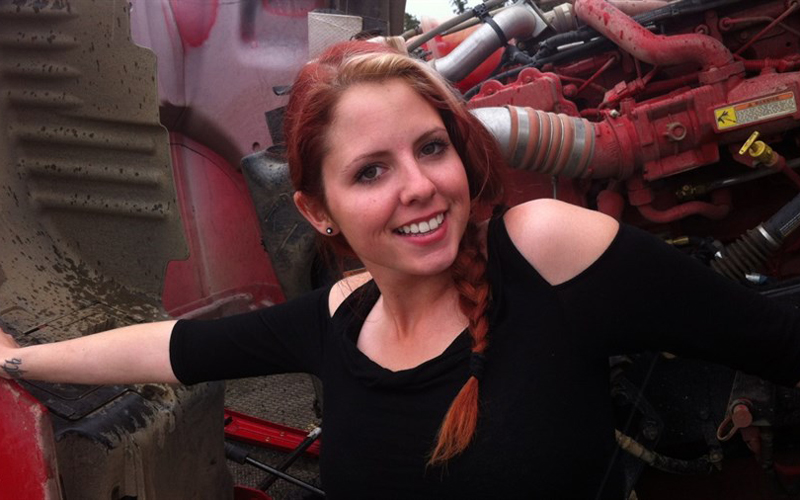 An image of a female with red hair, in front of a ATV smiling and posing for the camera.