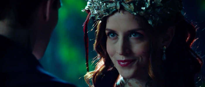 Red-haired woman wearing leafy crown looks at a man 