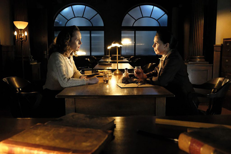 Two women sit at a table at night.