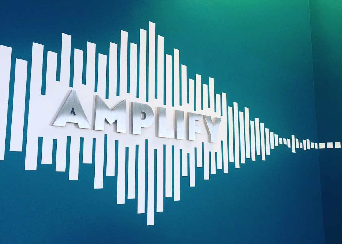 Blue and white wall with 'Amplify' in metal letters.