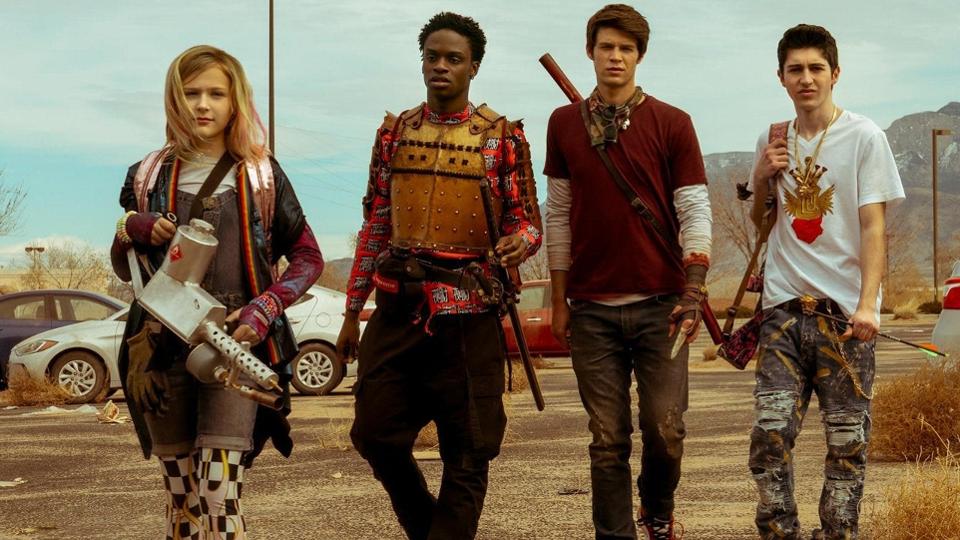 Four teenagers walking side-by-side holding various weapons