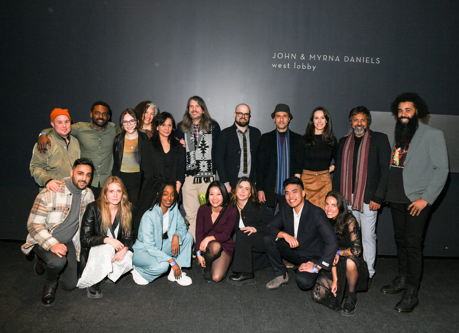 19 filmmakers posing in front of a grey background